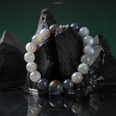 Pietersite Empower Bracelet with polished gray moonstone, iolite, and striking pietersite beads on a dark stone background.